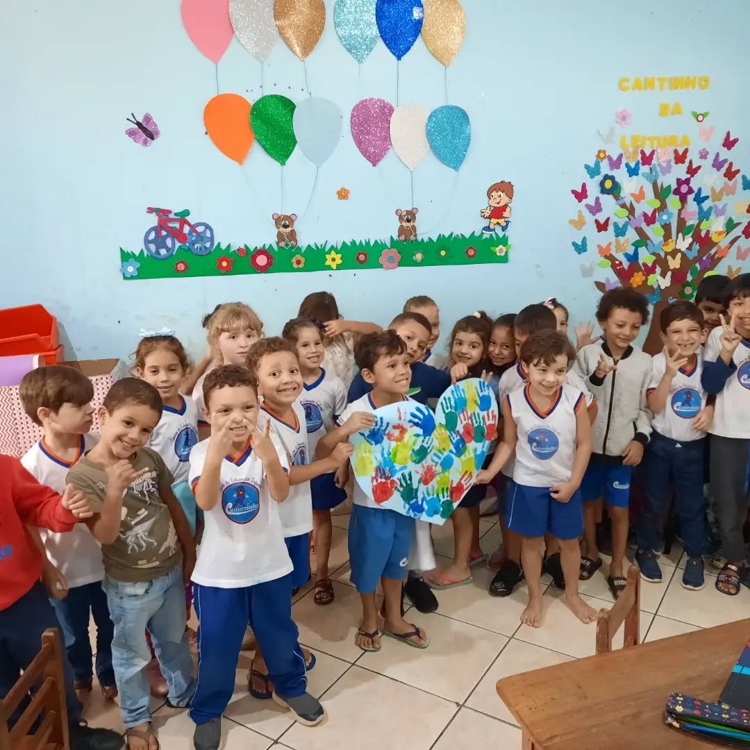 Crianças do CEI Castorzinho na sala do Cantinho da Leitura, segurando um coração pintado com as mãos